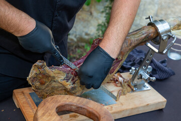Professional hands chef with gloves slicing iberico spanish ham in restaurant event party
