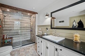 Nicely furnished bathroom interior with a glass door shower and a horizontal, long mirror by sink