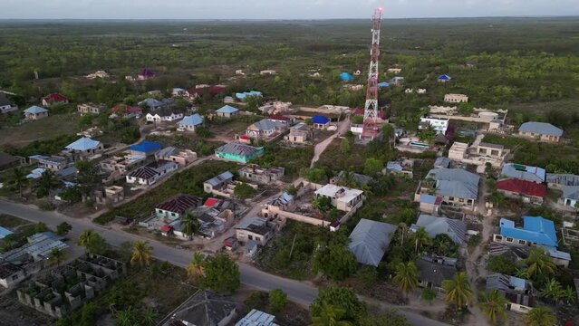 Radio communications tower and homes in Uroa Beach Zanzibar Tanzania Africa, Aerial orbit around shot