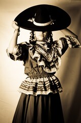 Retrato de una mujer modelo adolescente vistiendo un traje típico de Adelita de la Revolución Mexicana, y un sombrero de charro.