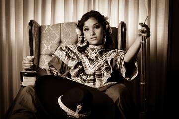 Retrato de una bella mujer adolescente mexicana latina sentada mientras viste un traje típico de...