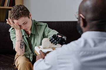Young woman with disability crying during psychotherapy session while psychotherapist giving her...