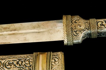 Antique dagger with artistic chasing and engraving on a black background