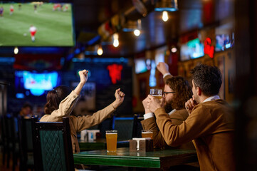 Close-up of friends group toasting with beer while sitting in beer pub together