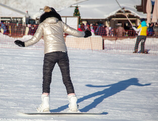 A woman slides down the mountain on a snowboard in the snow.