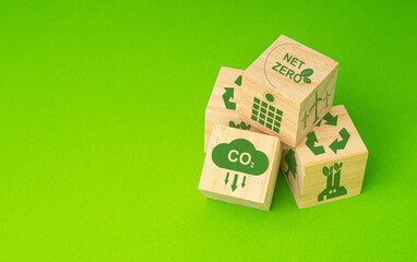 Wooden cubes with eco-friendly icons on a green background. Net-zero emissions in 2050