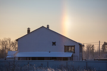 House with snow on the roof at sunset.