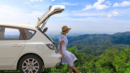 Woman relaxing inside the white hatchback car trunk at the mountains landscape and watching with...