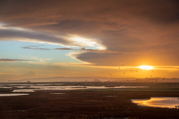 Fototapeta na wymiar Moody stormy colourful sunset skies over Rye Harbour nature reserve on the East Sussex coast south east England