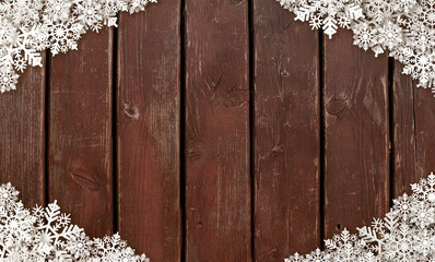 Papercut snowflakes arranged on a weathered wooden floor with copy space for additional content.