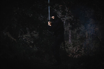Ninja silent killer waits in ambush in forest undergrowth