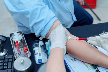 Doctor or nurse hand in white nitrile glove was using syringe to draw blood from patient's arm for taking a blood sample to examination and use a cotton swab moistened with alcohol to clean wound.