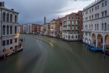 View from the Rialto Bridge with facades of picturesque old buildings on the Grand Canal, gondolas and boats in Venice.