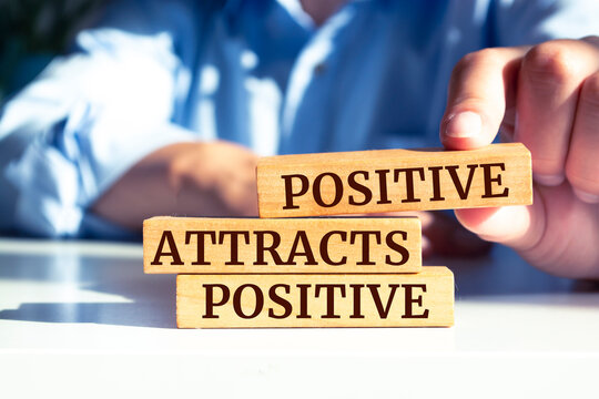 Wooden blocks with words 'Positive Attracts Positive'.