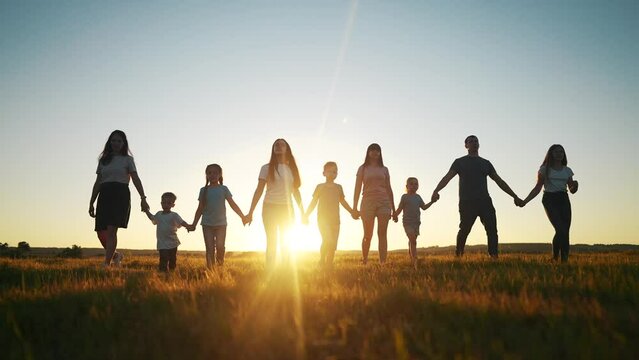 community large family in the park. a large group of people holding hands walking silhouette on nature sunset in the park lifestyle. big family kid dream concept. people in the park. large family