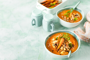 Pumpkin cream soup. Pumpkin and carrot puree soup with chickpeas and quinoa on a green background. Vegetarian cuisine. Vegan recipes.