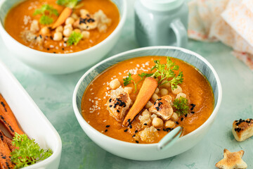 Pumpkin cream soup. Pumpkin and carrot puree soup with chickpeas and quinoa on a green background. Vegetarian cuisine. Vegan recipes.