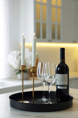 Pair of beautiful golden candlesticks and wine on white marble table in kitchen