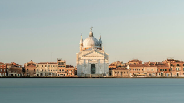 Chiesa del Santissimo Redentore catholic church and row of buildings on fondamenta embankment of Giudecca island canal in Venetian Lagoon, at sunrise, from Venice city, Veneto region, Northern Italy