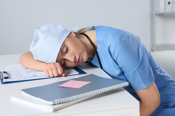 Tired young doctor sleeping at workplace in office