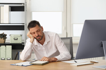 Fototapeta premium Sleepy man snoozing at workplace in office