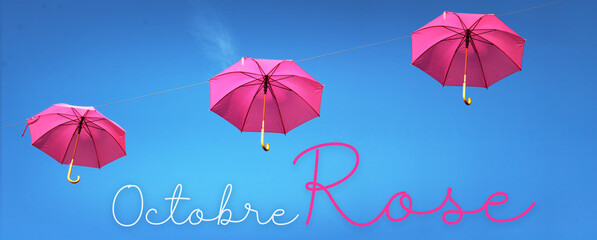 Octobre rose, parapluie rose dans le ciel bleu, concept bannière - obrazy, fototapety, plakaty