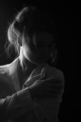 Obraz premium Black and white portrait of an attractive girl on a black studio background. Vertical Orientation