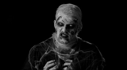 Frightening man with Halloween zombie bloody wounded face make-up, scared by police lights. Horror...