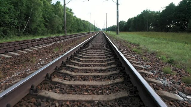 Moving forward on empty flat straight intercity railway tracks. Transportation and delivery of goods. Public rail transport for passengers. Flying at speed over rails and sleepers, point of view.