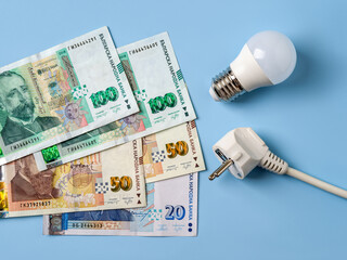 Electric plug, light bulb and  over blue background. Increasing of electricity costs in Bulgaria....