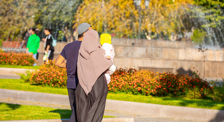 Muslim family spend time together in the park. Girl in a hijab. Romantic Muslim couple in love with a baby in their arms.