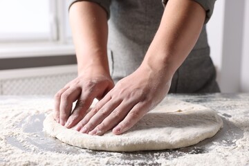 Obraz na płótnie Canvas Man kneading dough at table in kitchen, closeup