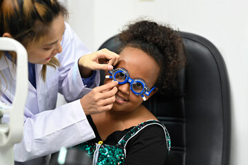 Smiling African woman checking eye vision with pediatric ophthalmologist. Eye health check and ophthalmology concept