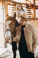 Couple in love riding horses on ranch at sunset in winter.