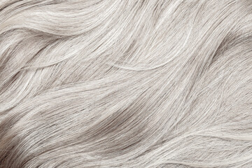 Blond hair close-up as a background. Women's long blonde hair. Beautifully styled wavy shiny curls....