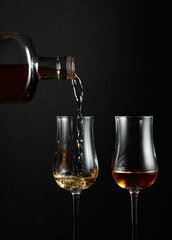 Strong alcohol drink is poured from a bottle into a glass.