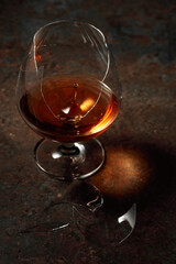 The drop of brandy falls into a broken glass.
