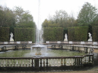 Scenic view with fountain in the park on a cloudy autumn day. People like healthy lifestyle and walking outdoors in luxury royal garden. Beautiful fall season scape. Fresh background of water drops.