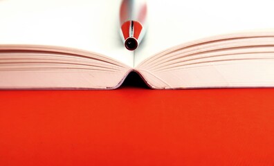 Pen in open notebook isolated on copy space orange background, selected focus on pen in center -...