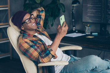 Photo of cool positive businessman dressed hat glasses reading news modern device indoors workplace...