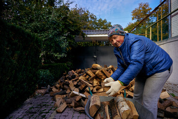 Mature pretty woman is loading firewood on a cart in Odessa Ukraine