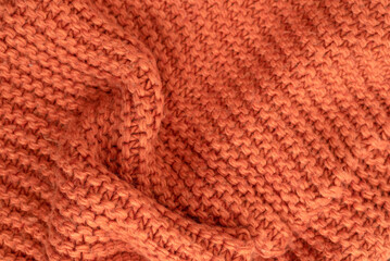 Orange knitted fabric texture abstract background. A slightly crumpled knitted blanket made of woolen threads. Winter or autumn warm background