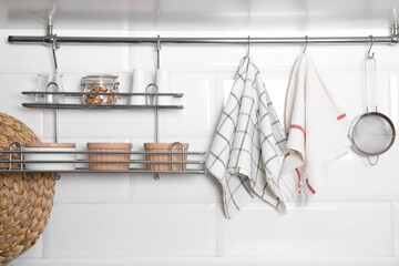 Different kitchen towels hanging on hook rod and shelves with ramekins indoors