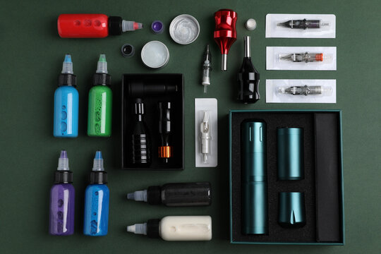 Flat lay composition with tattoo equipment on dark green background