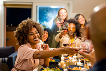 Mixed age range group of friends toasting at dinner party, focus on woman face, Brazilian people...