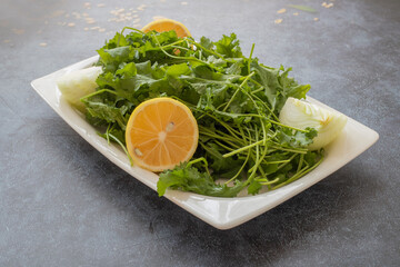 Fresh cress salad in a white plate on a gray stone background .