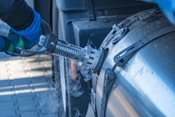 Ein LKW Fahrer zieht nach dem LNG tanken den Tankschlauch aus dem LNG Tank