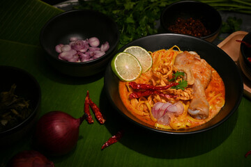 Delicious Thai curry noodles with chicken drumstick and vegetables or Khao Soi Kai.