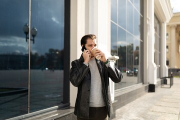 35 year old man talking on the phone while drinking coffee in the city