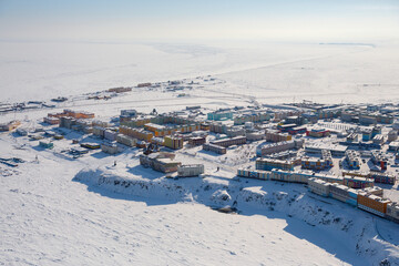 Winter aerial photograph of a snow-covered town in the Arctic. Top view of the city of Anadyr, located on the coast of the Anadyr Estuary, surrounded by tundra. Cold polar climate. Chukotka, Russia.